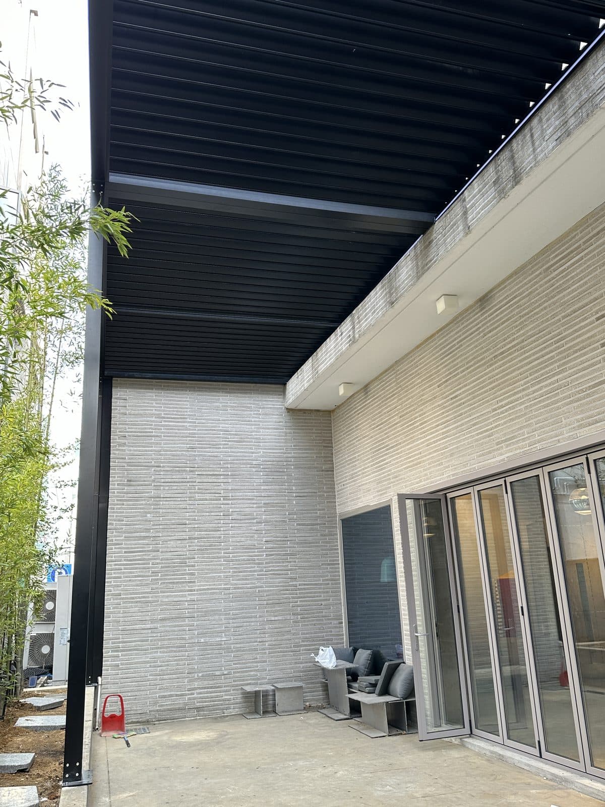 서울 강남구 검은색 루버 파고라 아래 건물 유리 슬라이딩 도어와 외부 공간