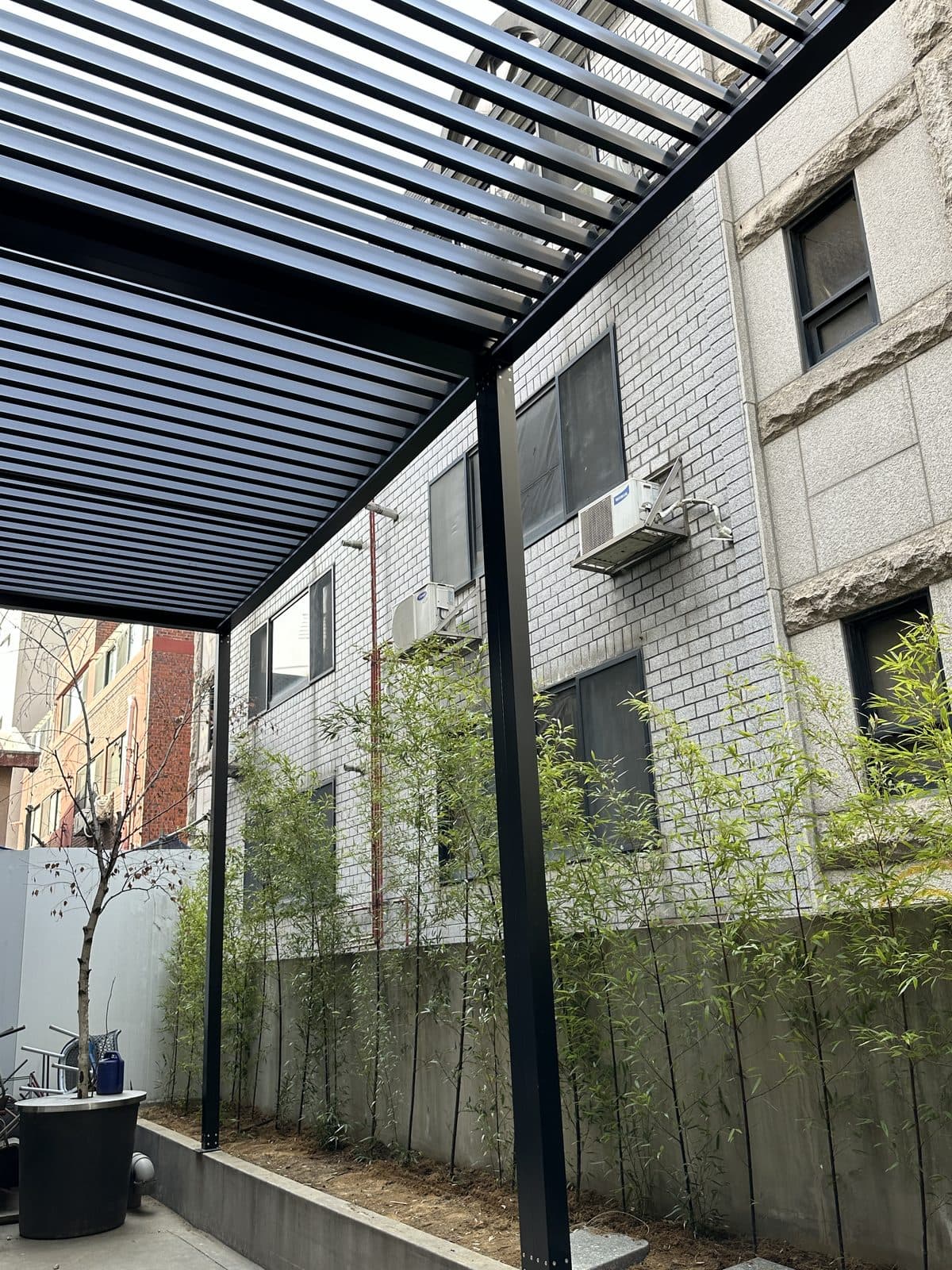 서울 강남구 외부 공간 검은색 루버 파고라 기둥과 루버 천장