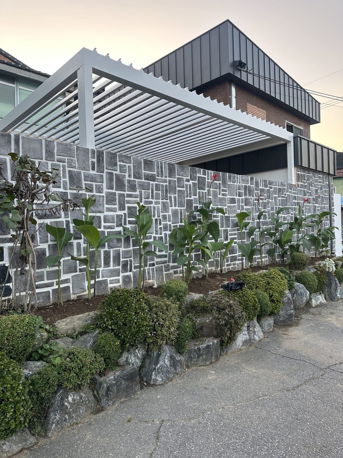 용인 주택 석재 벽 위에 설치한 흰색 루버 파고라