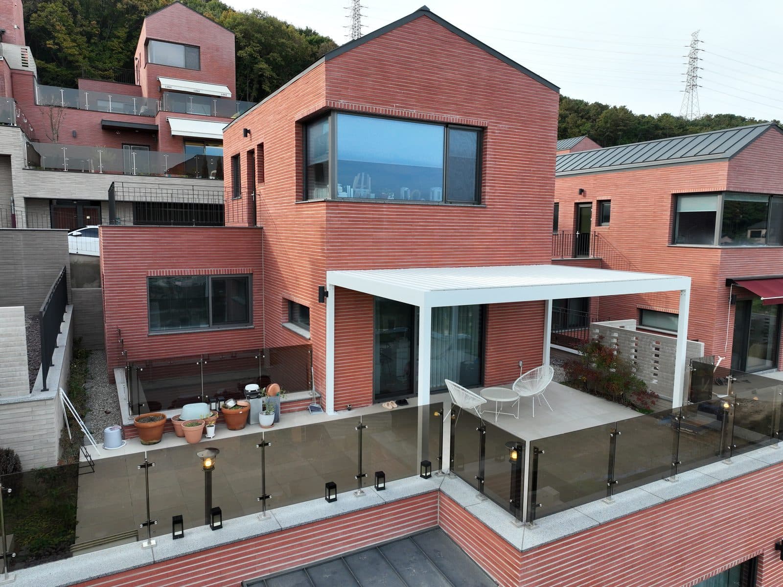 용인 타운하우스 2층 테라스의 흰색 루버 파고라와 유리 난간
